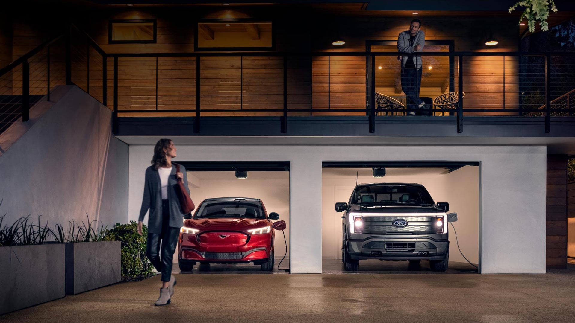 Woman walking out from home garage with a 2024 Mustang® Mach-E and Ford Lightning® truck in plugged-in and charging | Krause Family Ford of Woodstock in Woodstock GA